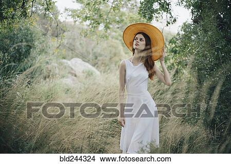 Caucasian woman wearing hat walking in tall grass View Large Photo Image Picture - Caucasian woman wearing hat walking in tall grass. Fotosearch
