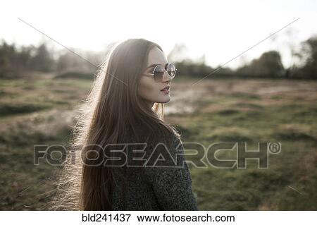 Stock Photo - Caucasian woman wearing sunglasses in field. Fotosearch