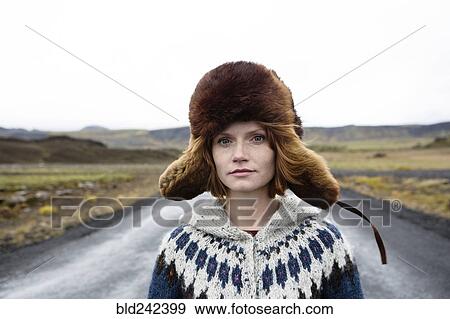 Stock Photo - Caucasian woman wearing sweater and fur hat in middle of road. Fotosearch