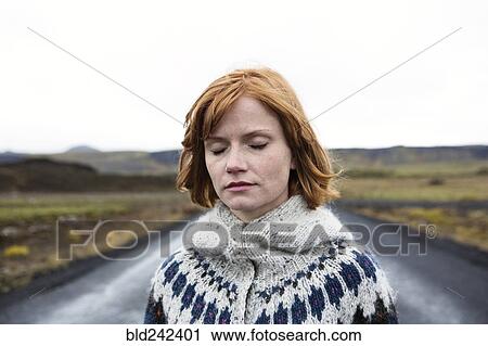 Stock Image - Caucasian woman wearing sweater in road. Fotosearch