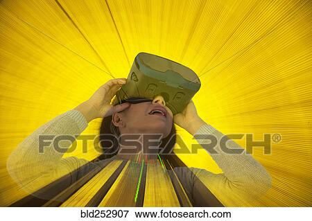 Stock Photo - Caucasian woman wearing virtual reality goggles. Fotosearch