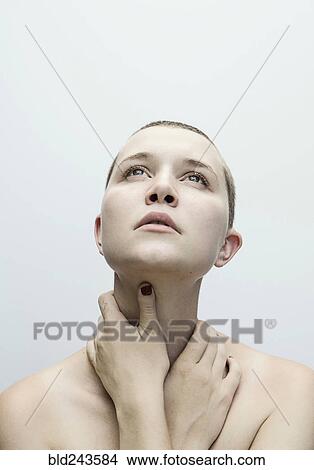 Picture - Caucasian woman with shaved-head holding neck with hands. Fotosearch