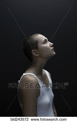 Stock Image - Caucasian woman with shaved-head looking up. Fotosearch