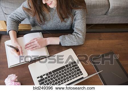 Stock Photograph - Caucasian woman writing in notebook. Fotosearch