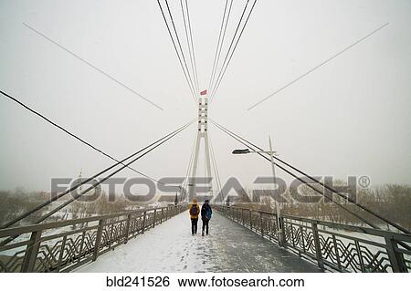 Stock Photograph - Caucasian women crossing bridge in winter. Fotosearch