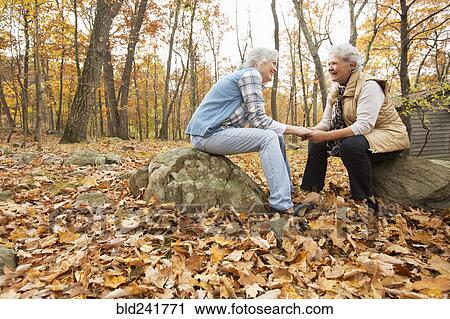 Stock Image - Caucasian women holding hands outdoors in autumn. Fotosearch