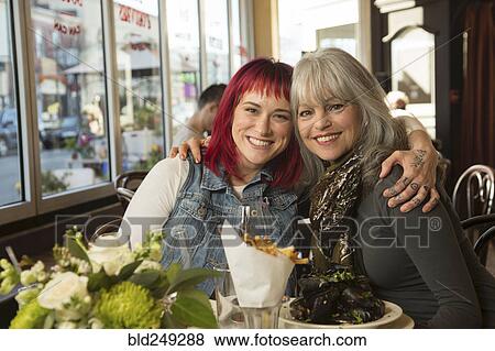 Stock Photo - Caucasian women hugging in restaurant. Fotosearch