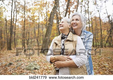 Stock Photo - Caucasian women hugging outdoors in autumn. Fotosearch