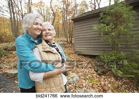Caucasian women hugging outdoors near cabin View Large Photo Image Stock Photograph - Caucasian women hugging outdoors near cabin. Fotosearch