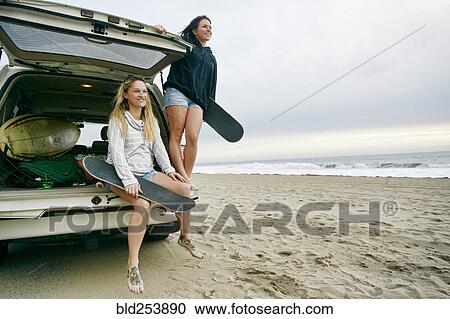 Caucasian women in car hatch at beach holding skateboards View Large Photo Image Stock Image - Caucasian women in car hatch at beach holding skateboards. Fotosearch