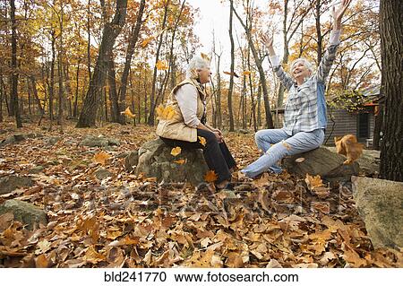 Stock Image - Caucasian women playing with autumn leaves. Fotosearch
