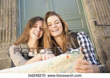 Stock Image - Caucasian women reading map. Fotosearch