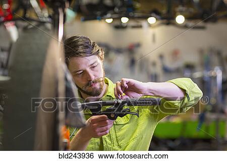 Stock Photograph - Caucasian worker repairing bicycle handlebar in shop. Fotosearch
