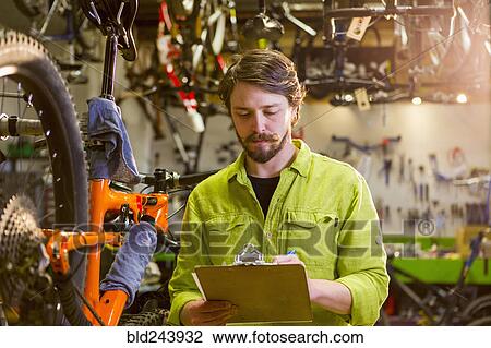 Caucasian worker writing on clipboard in bicycle shop View Large Photo Image Stock Image - Caucasian worker writing on clipboard in bicycle shop. Fotosearch