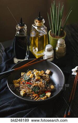 Stock Photo - Chopsticks on the bowl with noodles and tofu. Fotosearch