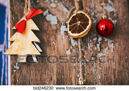 Stock Image - Christmas ornaments hanging on wood. Fotosearch