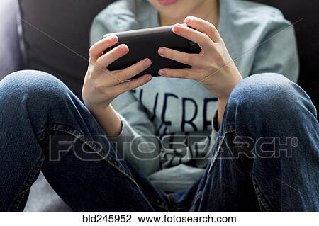 Stock Image - Close up of Caucasian boy playing with cell phone. Fotosearch
