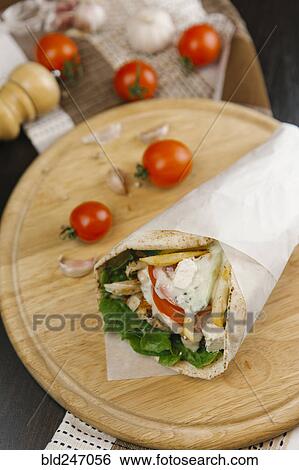 Close up of shawarma wrap on cutting board View Large Photo Image Stock Photograph - Close up of shawarma wrap on cutting board. Fotosearch
