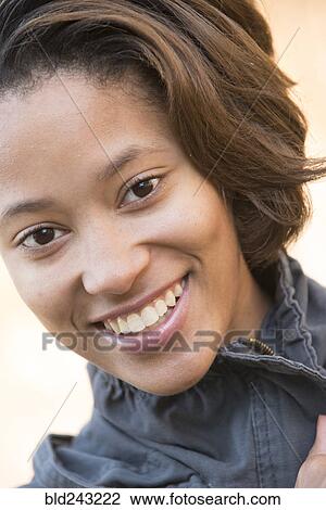 Stock Image - Close up of smiling Mixed Race woman. Fotosearch