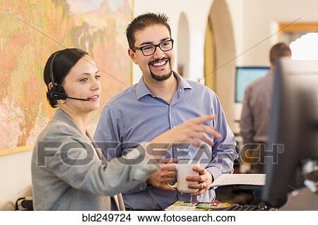 Co-workers talking in office near computer View Large Photo Image Picture - Co-workers talking in office near computer. Fotosearch
