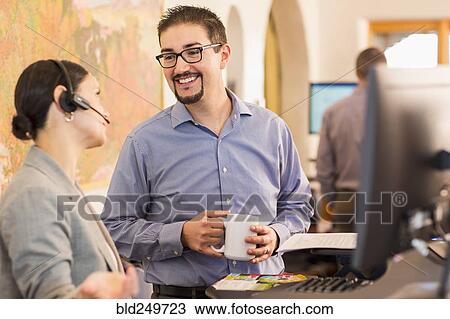 Co-workers talking in office near computer View Large Photo Image Stock Image - Co-workers talking in office near computer. Fotosearch