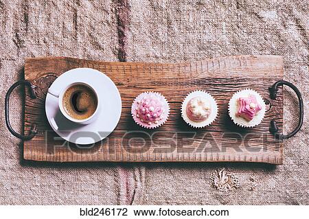 Stock Image - Coffee and cupcakes on wooden tray. Fotosearch