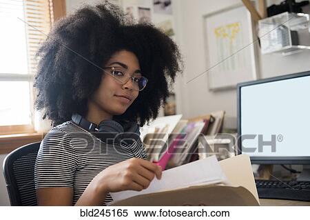 Confident African American woman holding files near computer View Large Photo Image Stock Photography - Confident African American woman holding files near computer. Fotosearch