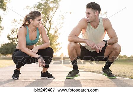 Stock Photo - Couple crouching on path in park and resting. Fotosearch