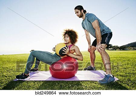 Couple exercising with fitness ball and heavy ball in sunny field View Large Photo Image Picture - Couple exercising with fitness ball and heavy ball in sunny field. Fotosearch