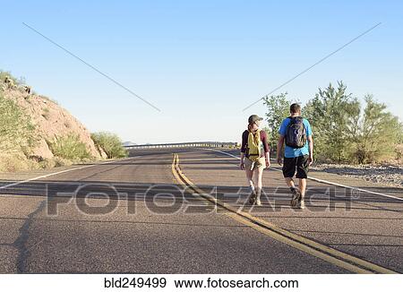 Couple hiking on winding street View Large Photo Image Stock Photo - Couple hiking on winding street. Fotosearch
