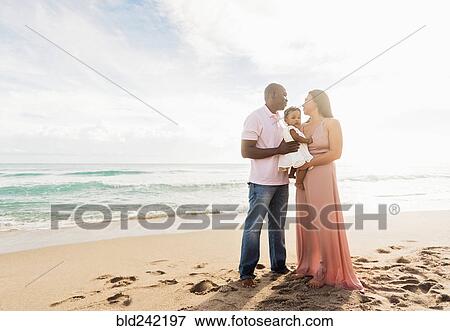 Stock Photo - Couple holding baby daughter on beach. Fotosearch