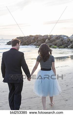 Stock Photography - Couple holding hands and walking on beach. Fotosearch