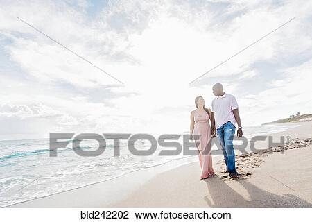 Couple holding hands walking on beach View Large Photo Image Stock Image - Couple holding hands walking on beach. Fotosearch