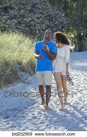 Couple laughing and walking on beach View Large Photo Image Stock Photo - Couple laughing and walking on beach. Fotosearch