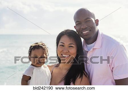 Couple posing near ocean with baby daughter View Large Photo Image Stock Image - Couple posing near ocean with baby daughter. Fotosearch