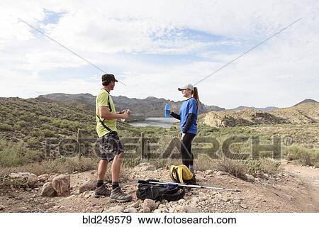 Stock Photo - Couple resting while hiking in desert. Fotosearch