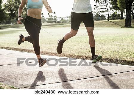 Stock Image - Couple running on path in park. Fotosearch