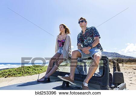 Couple sitting on windshield of convertible car on beach View Large Photo Image Stock Photograph - Couple sitting on windshield of convertible car on beach. Fotosearch