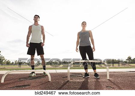 Stock Photo - Couple standing nears exercise bars outdoors. Fotosearch