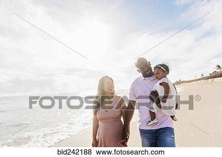 Stock Photo - Couple walking on beach with baby daughter. Fotosearch