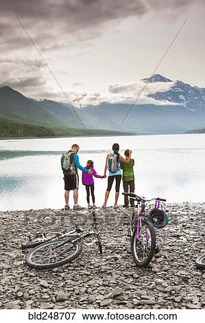 Couple with son and daughter riding bicycles near lake View Large Photo Image Stock Photo - Couple with son and daughter riding bicycles near lake. Fotosearch