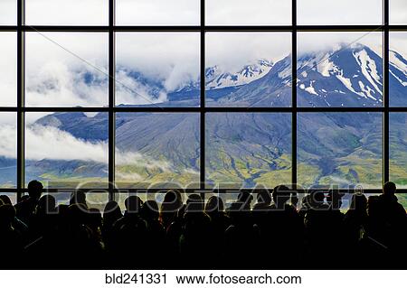 Stock Image - Crowd at window with scenic view of mountain. Fotosearch