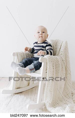 Curious Caucasian baby boy sitting in chair View Large Photo Image Stock Photo - Curious Caucasian baby boy sitting in chair. Fotosearch