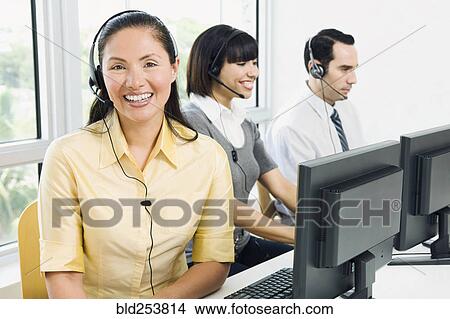 Picture - Customer service representatives wearing headsets using computers. Fotosearch