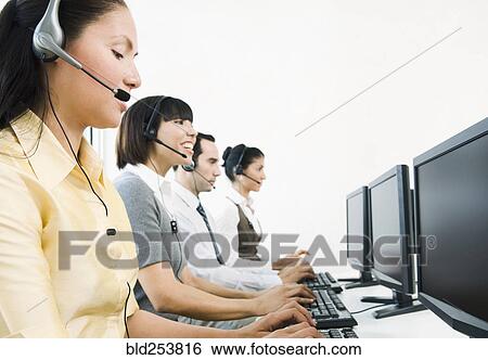 Stock Photograph - Customer service representatives wearing headsets using computers. Fotosearch