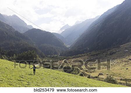 Distant carefree person walking on hill near mountains View Large Photo Image Stock Photo - Distant carefree person walking on hill near mountains. Fotosearch