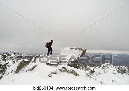 Picture - Distant Caucasian man standing on mountain in winter. Fotosearch