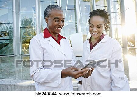 Doctors outdoors at hospital using digital tablet View Large Photo Image Picture - Doctors outdoors at hospital using digital tablet. Fotosearch