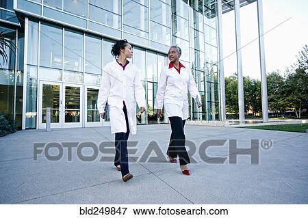 Doctors walking and talking outdoors at hospital View Large Photo Image Stock Photo - Doctors walking and talking outdoors at hospital. Fotosearch