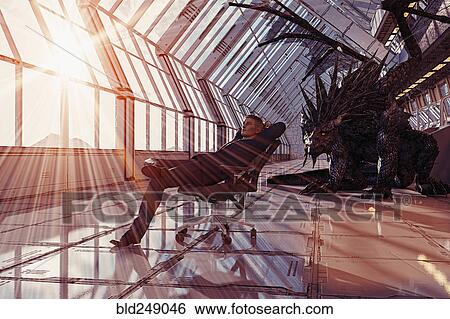 Stock Photograph - Dragon behind businessman leaning in chair. Fotosearch
